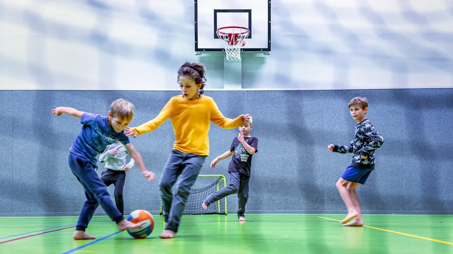 Kinderen van de BSO spelen samen voetbal in de gymzaal bij kinderopvang Kind&co ludens