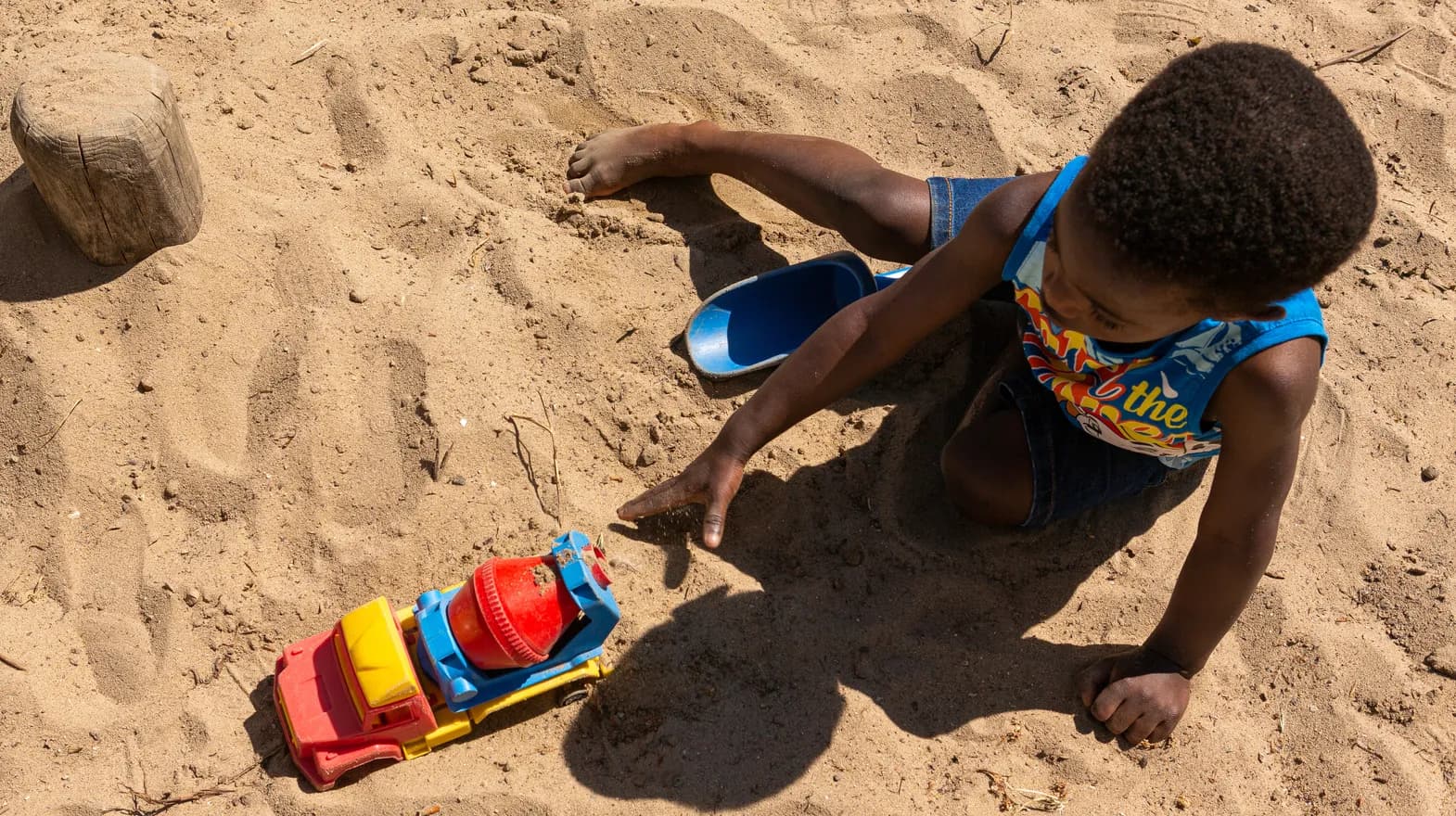 Kind van de peutergroep speelt buiten met zand bij kinderopvang Kind&co ludens