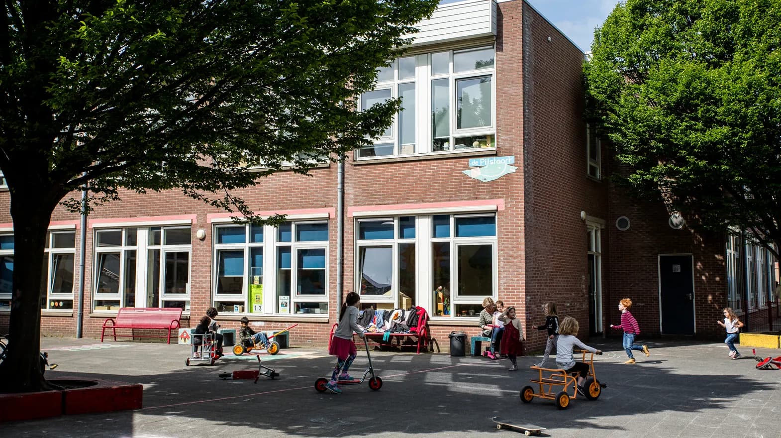 Spelende kinderen op het schoolplein van buitenschoolse opvang Maanvis, kinderopvang Kind&co Ludens