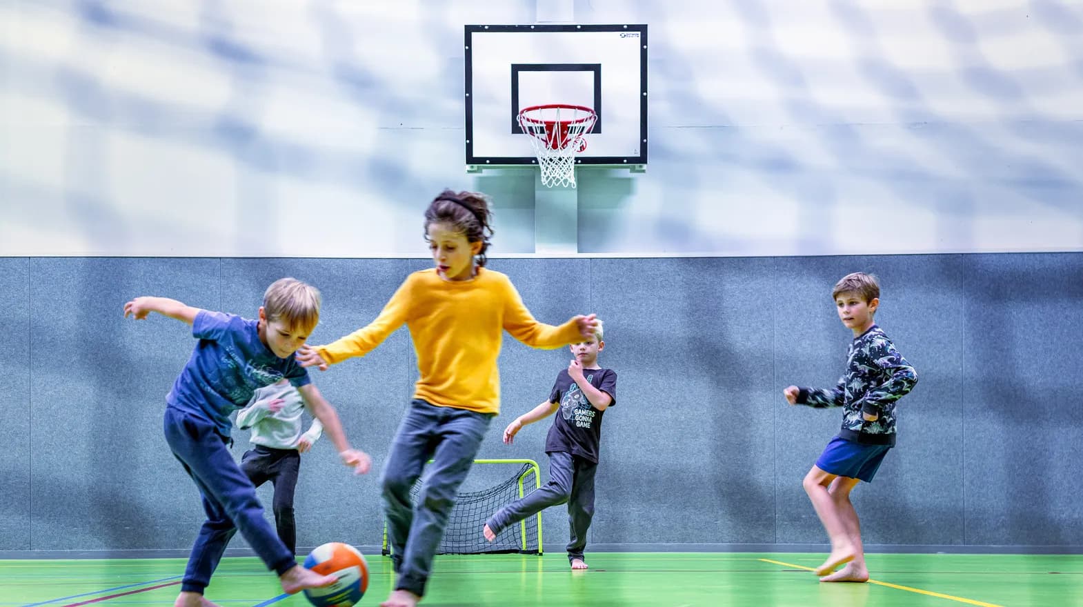 Kinderen van de BSO spelen samen voetbal in de gymzaal bij kinderopvang Kind&co ludens