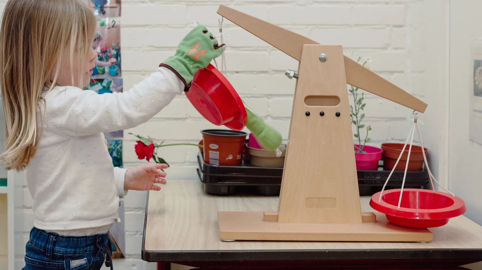 Een kind van de peutergroep speelt met een weegschaal bij kinderopvang Kind&co ludens