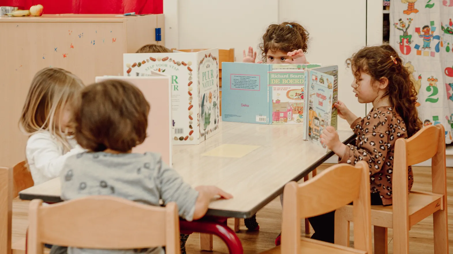 Kinderen van de peutergroep lezen samen aan tafel bij kinderopvang Kind&co ludens
