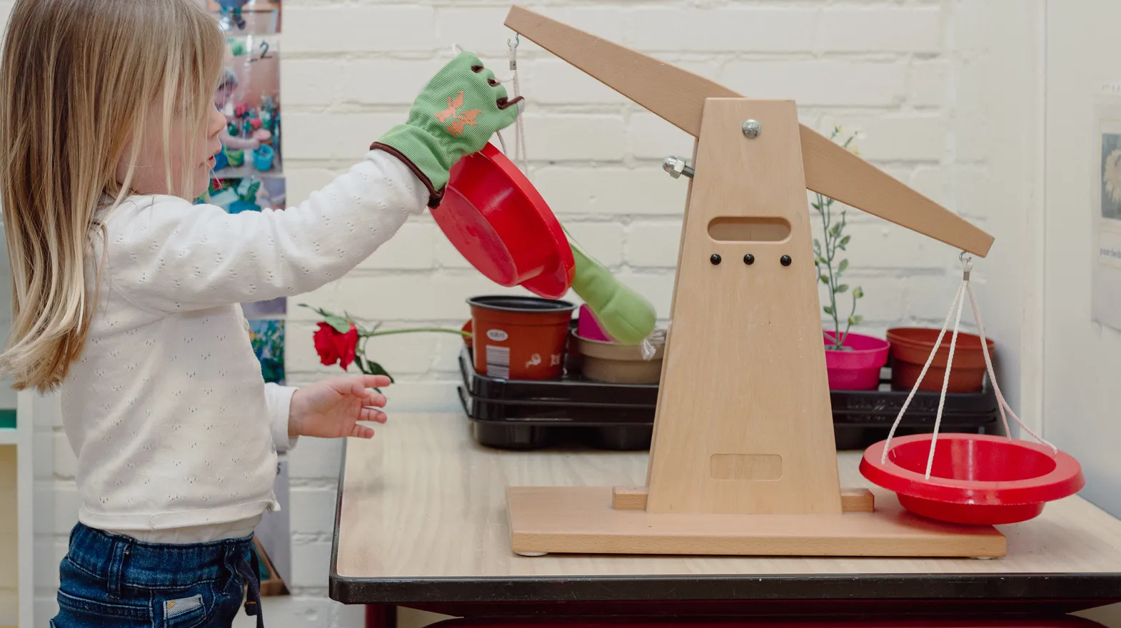 Een kind van de peutergroep speelt met een weegschaal bij kinderopvang Kind&co ludens