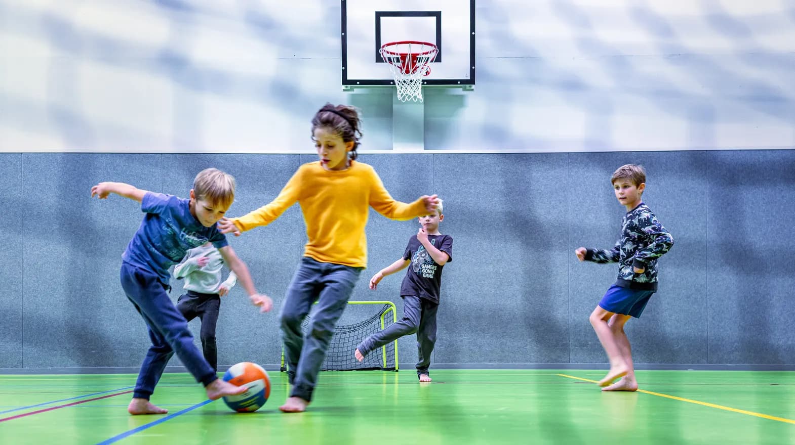 Kinderen van de BSO spelen samen voetbal in de gymzaal bij kinderopvang Kind&co ludens