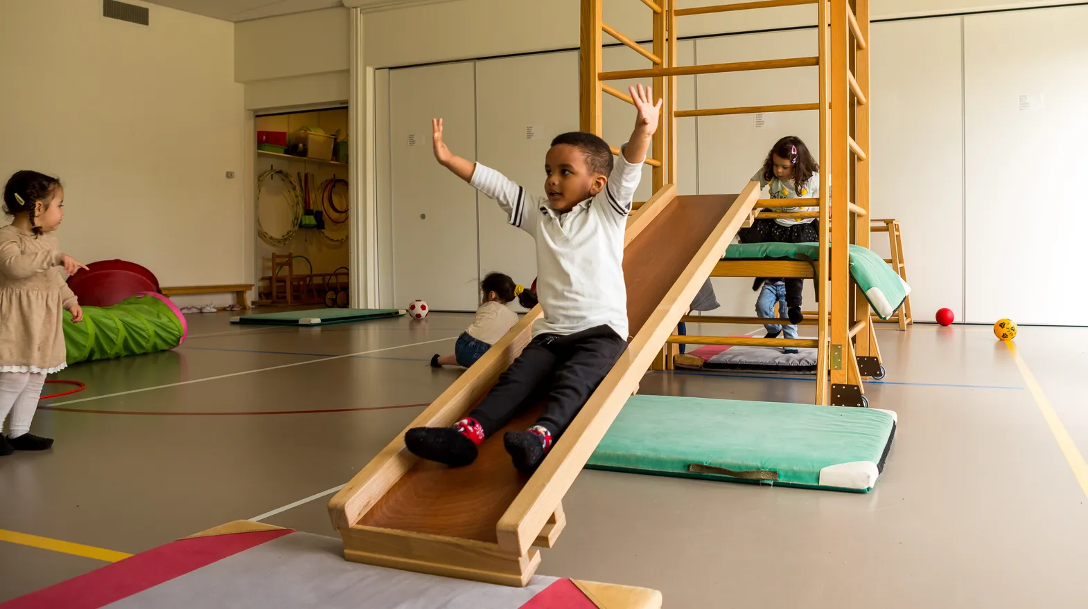Kinderen klimmen en glijden in gymzaal bij kinderopvang Kind&co ludens