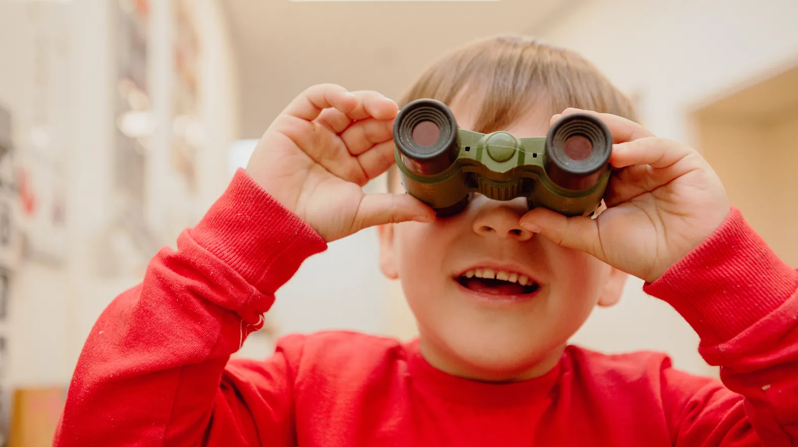 Kind kijkt door een verrekijker bij een Peutergroep van kinderopvang Kind&co ludens