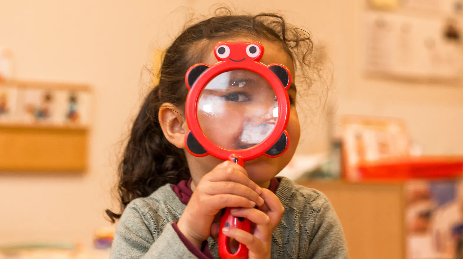 Kind op de peutergroep speelt met vergrootglas bij kinderopvang Kind&co ludens