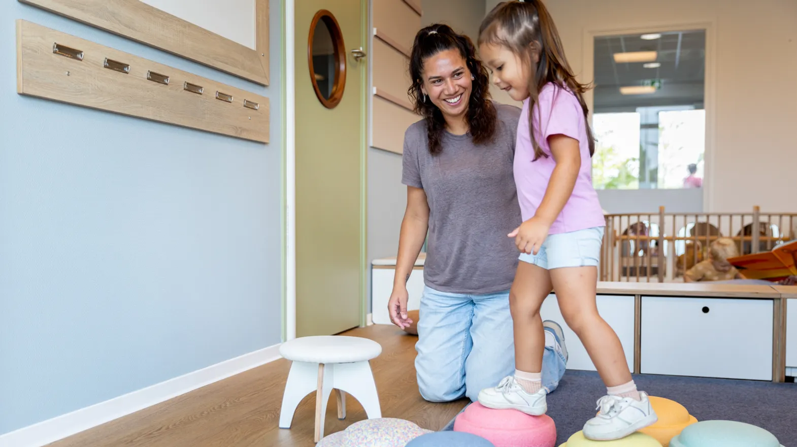 Kinderen spelen samen met pedagogisch medewerker met stapelstenen bij kinderopvang Kind&co ludens