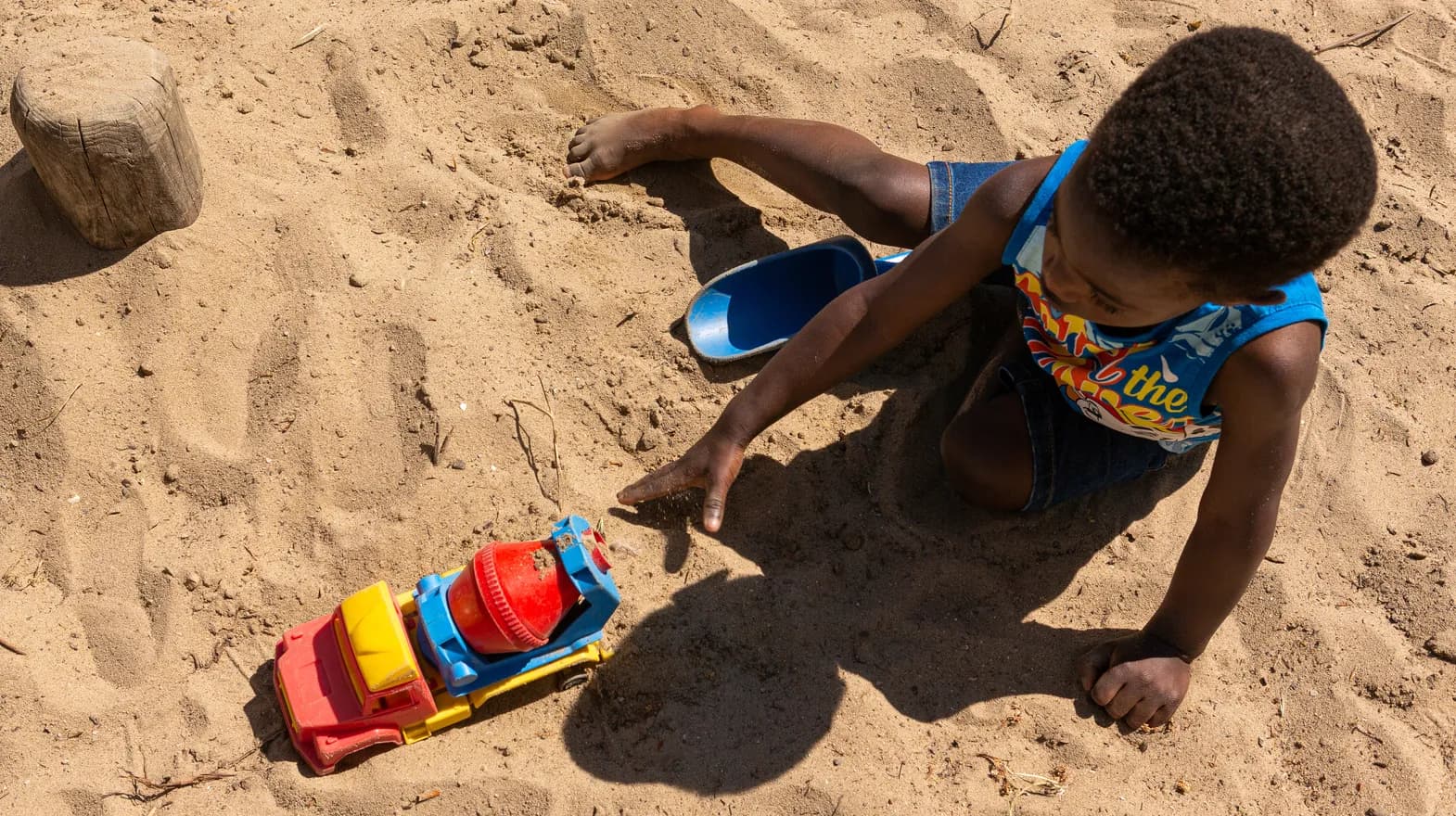 Kind van de peutergroep speelt buiten met zand bij kinderopvang Kind&co ludens