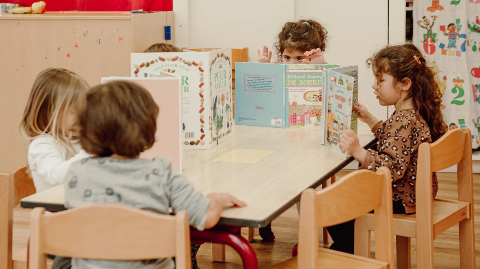 Kinderen van de peutergroep lezen samen aan tafel bij kinderopvang Kind&co ludens
