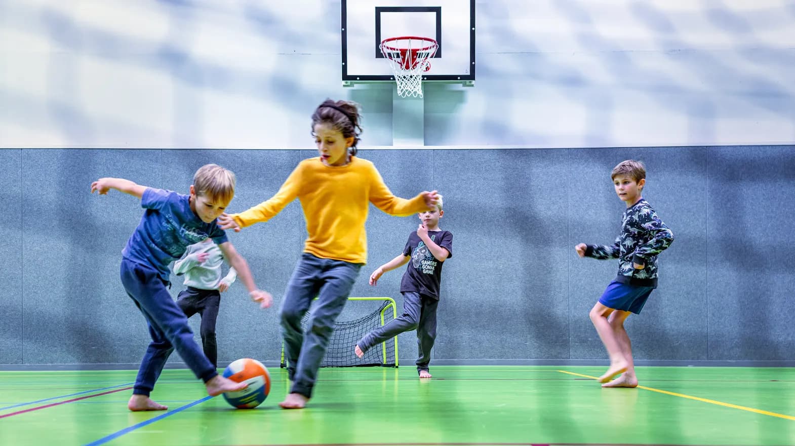 Kinderen van de BSO spelen samen voetbal in de gymzaal bij kinderopvang Kind&co ludens