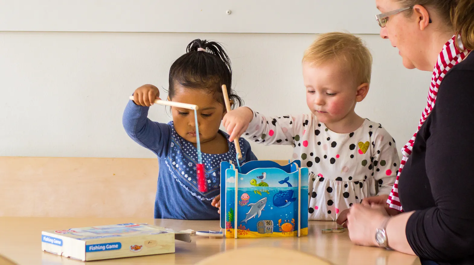 Kinderen spelen samen "Vissen" onder begeleiding van een pedagogisch medewerker bij kinderopvang Kind&co ludens