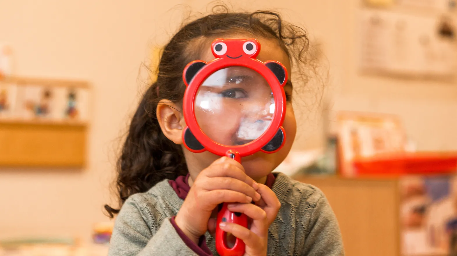 Kind op de peutergroep speelt met vergrootglas bij kinderopvang Kind&co ludens