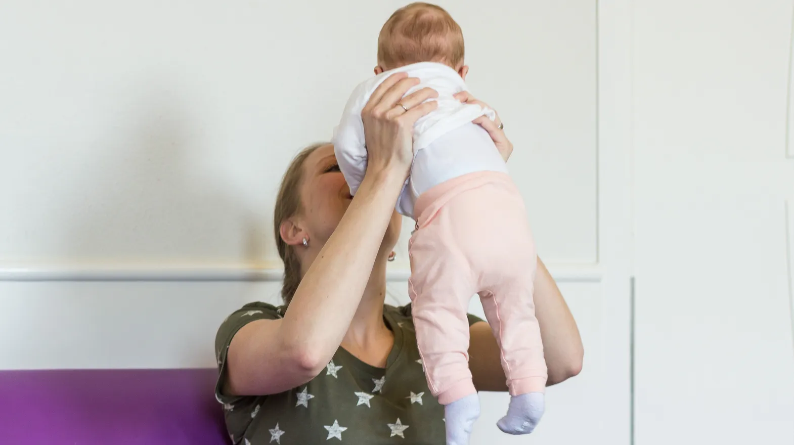 Pedagogisch medewerker knuffelt baby bij kinderdagverblijf Klavertje, kinderopvang Kind&co ludens