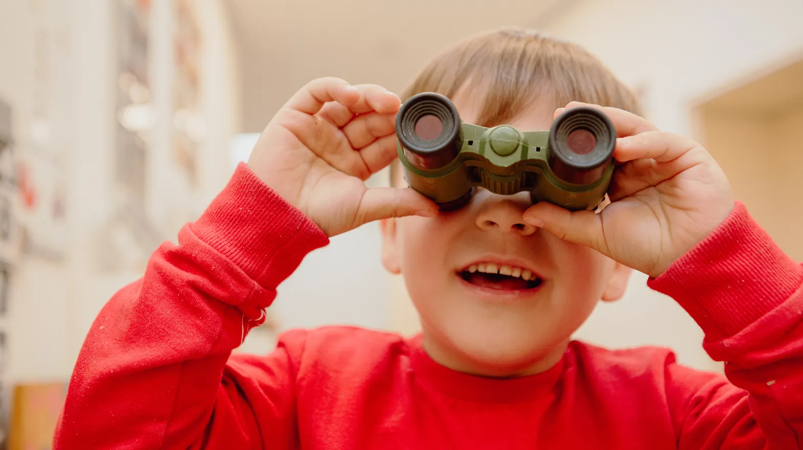 Kind kijkt door een verrekijker bij een Peutergroep van kinderopvang Kind&co ludens