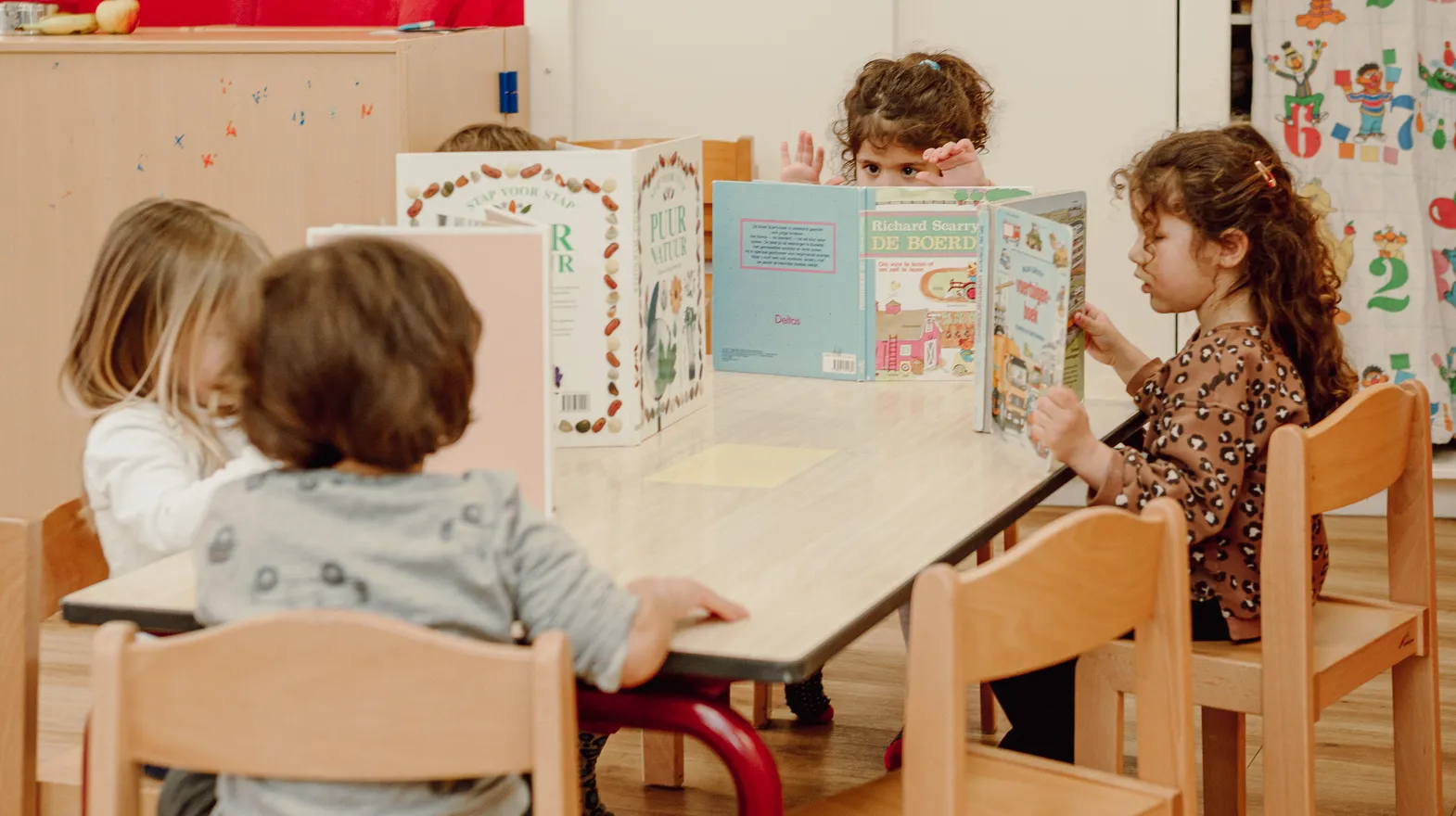 Kinderen van de peutergroep lezen samen aan tafel bij kinderopvang Kind&co ludens