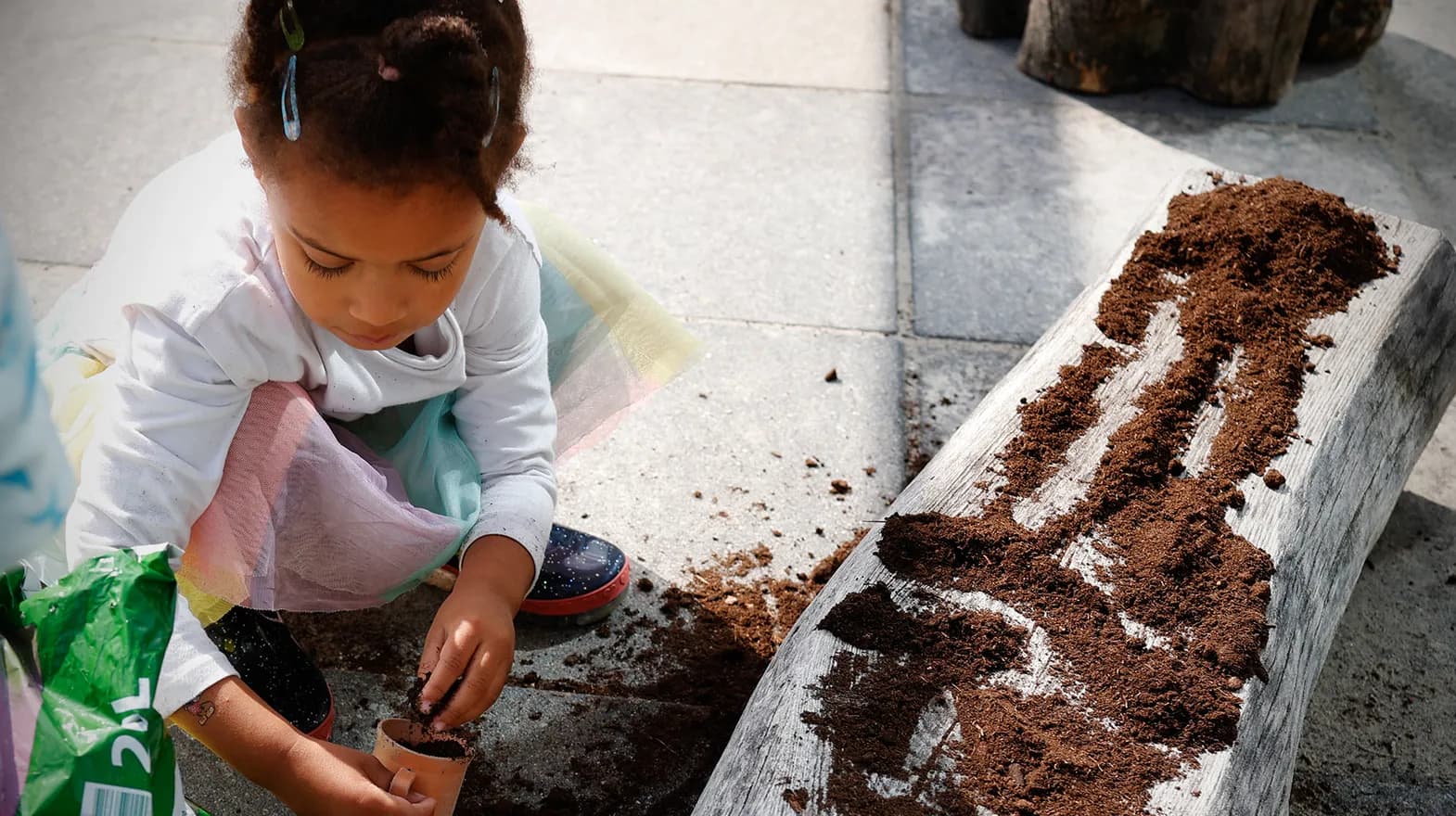 Kind van de peutergroep poot zaadjes in de moestuin bij kinderopvang Kind&co ludens