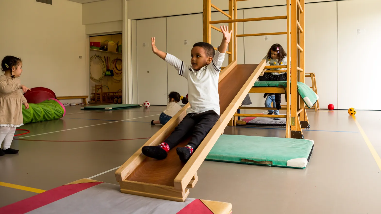 Kinderen klimmen en glijden in gymzaal bij kinderopvang Kind&co ludens