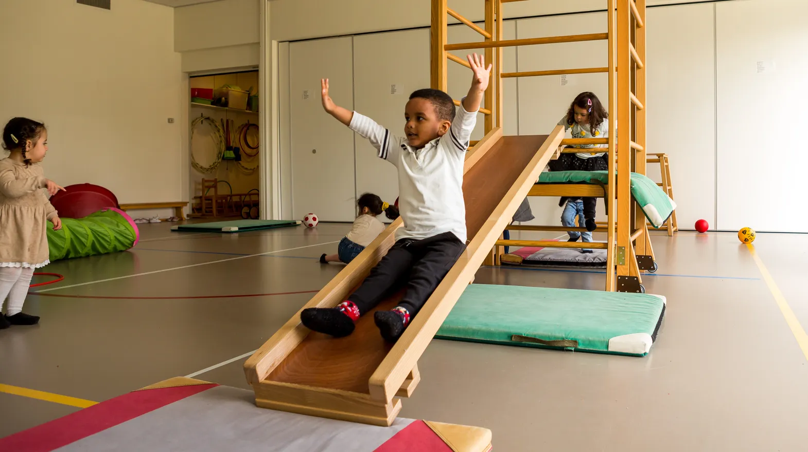 Kinderen klimmen en glijden in gymzaal bij kinderopvang Kind&co ludens