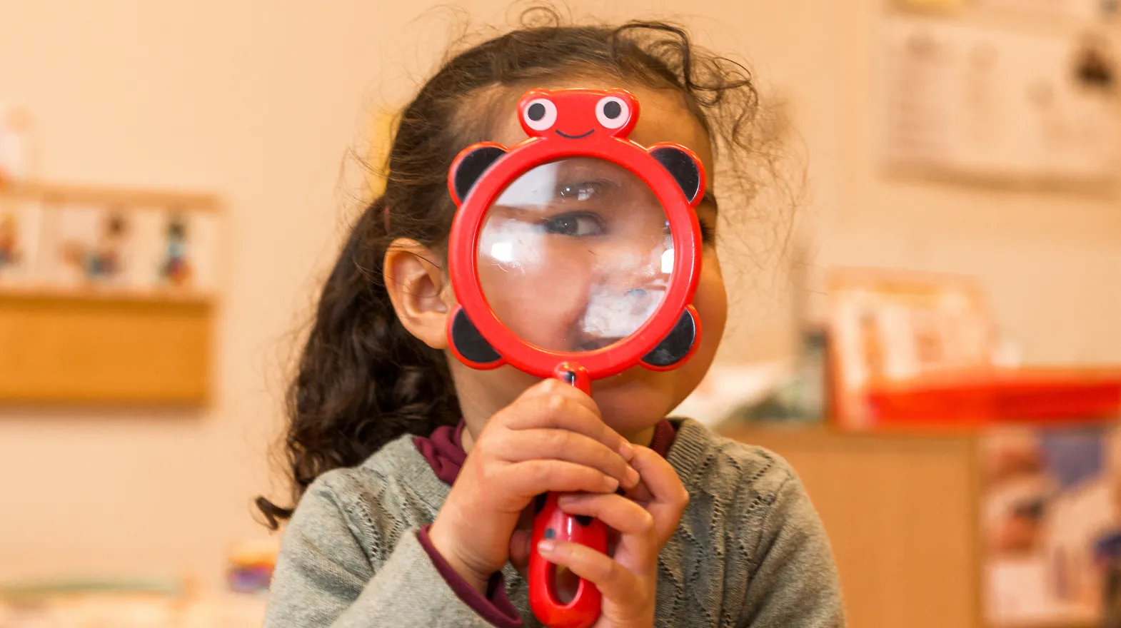 Kind op de peutergroep speelt met vergrootglas bij kinderopvang Kind&co ludens