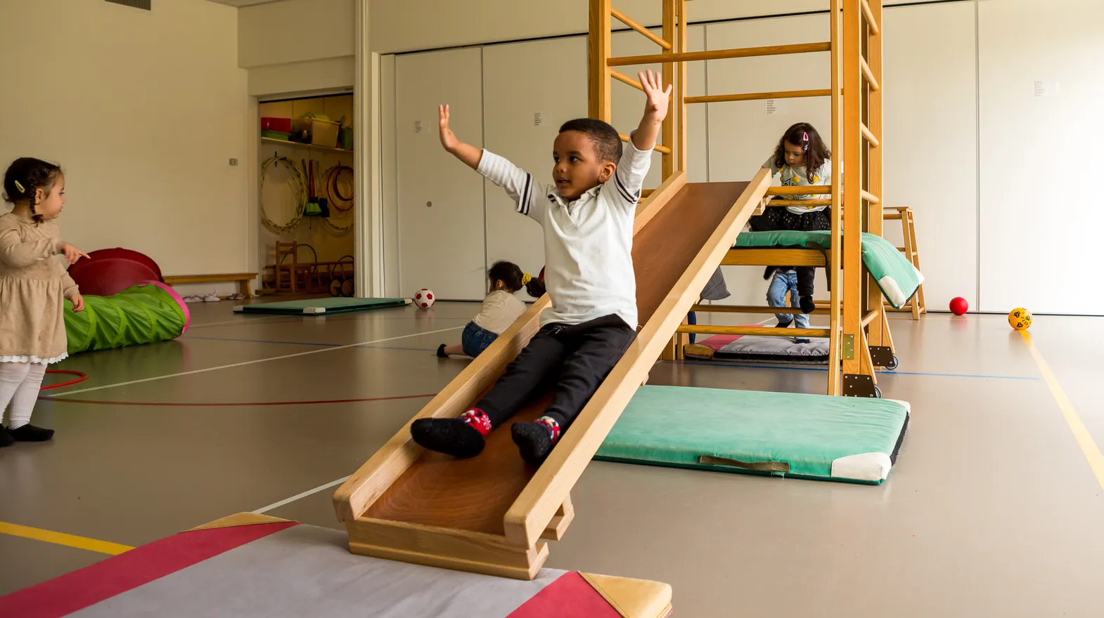 Kinderen klimmen en glijden in gymzaal bij kinderopvang Kind&co ludens