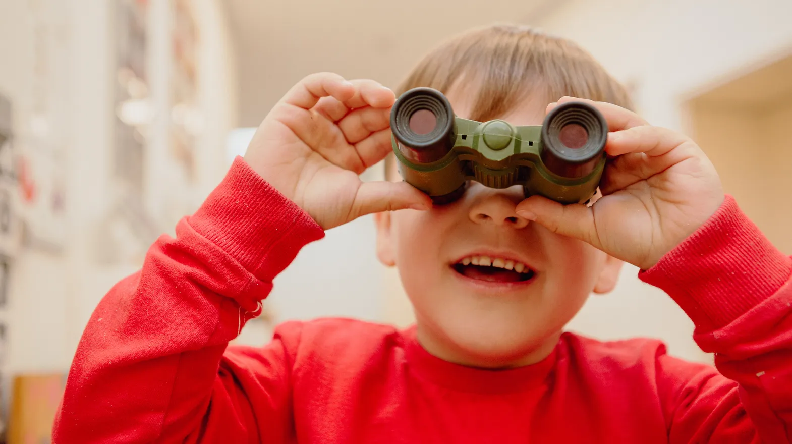 Kind kijkt door een verrekijker bij een Peutergroep van kinderopvang Kind&co ludens