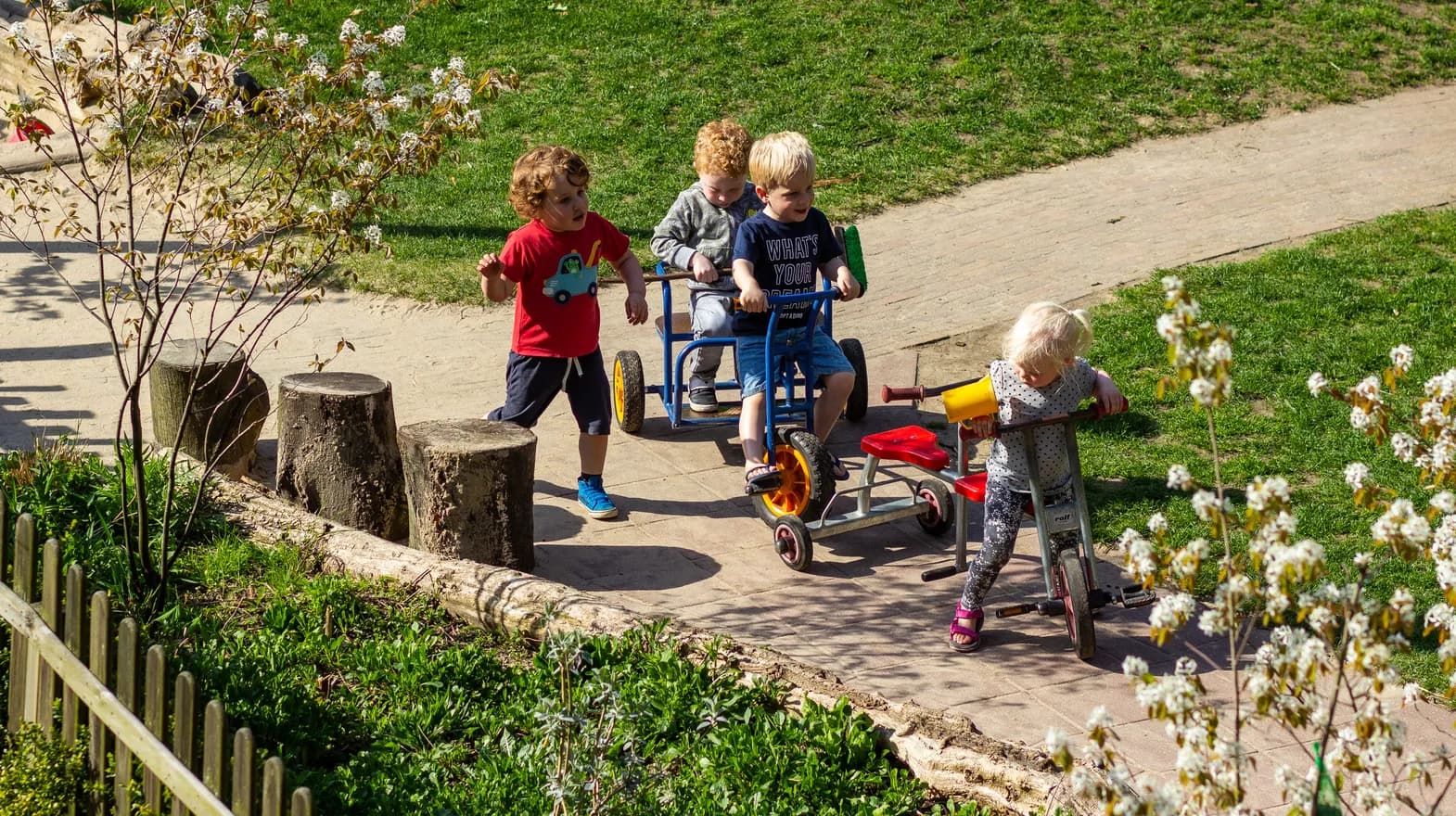 Kinderen fietsen in de tuin van kinderdagverblijf Klavertje, kinderopvang Kind&co ludens