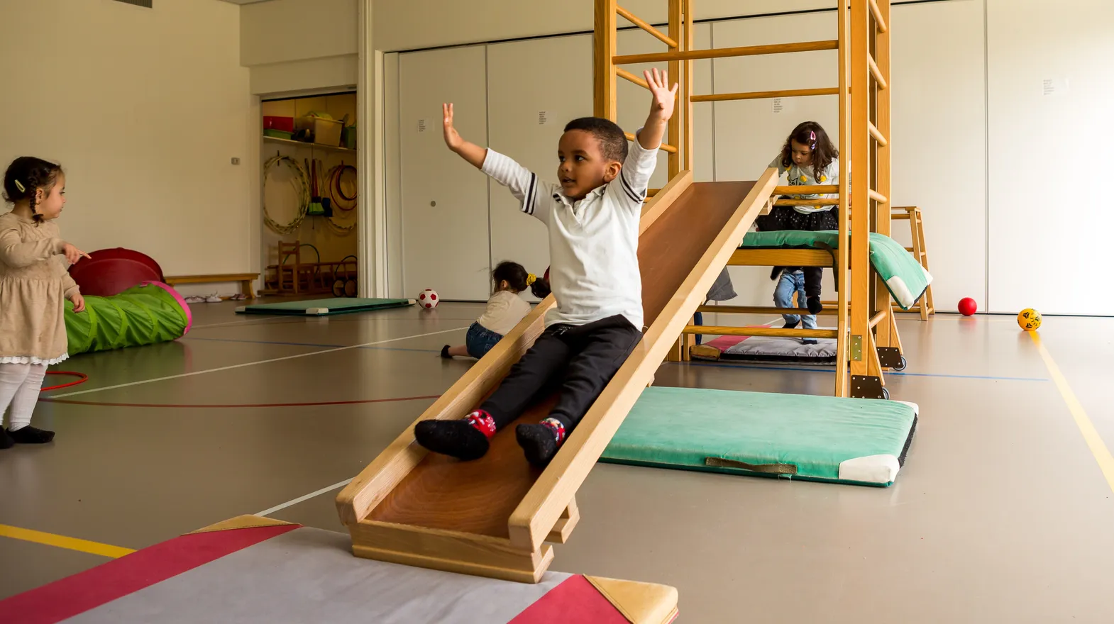 Kinderen klimmen en glijden in gymzaal bij kinderopvang Kind&co ludens
