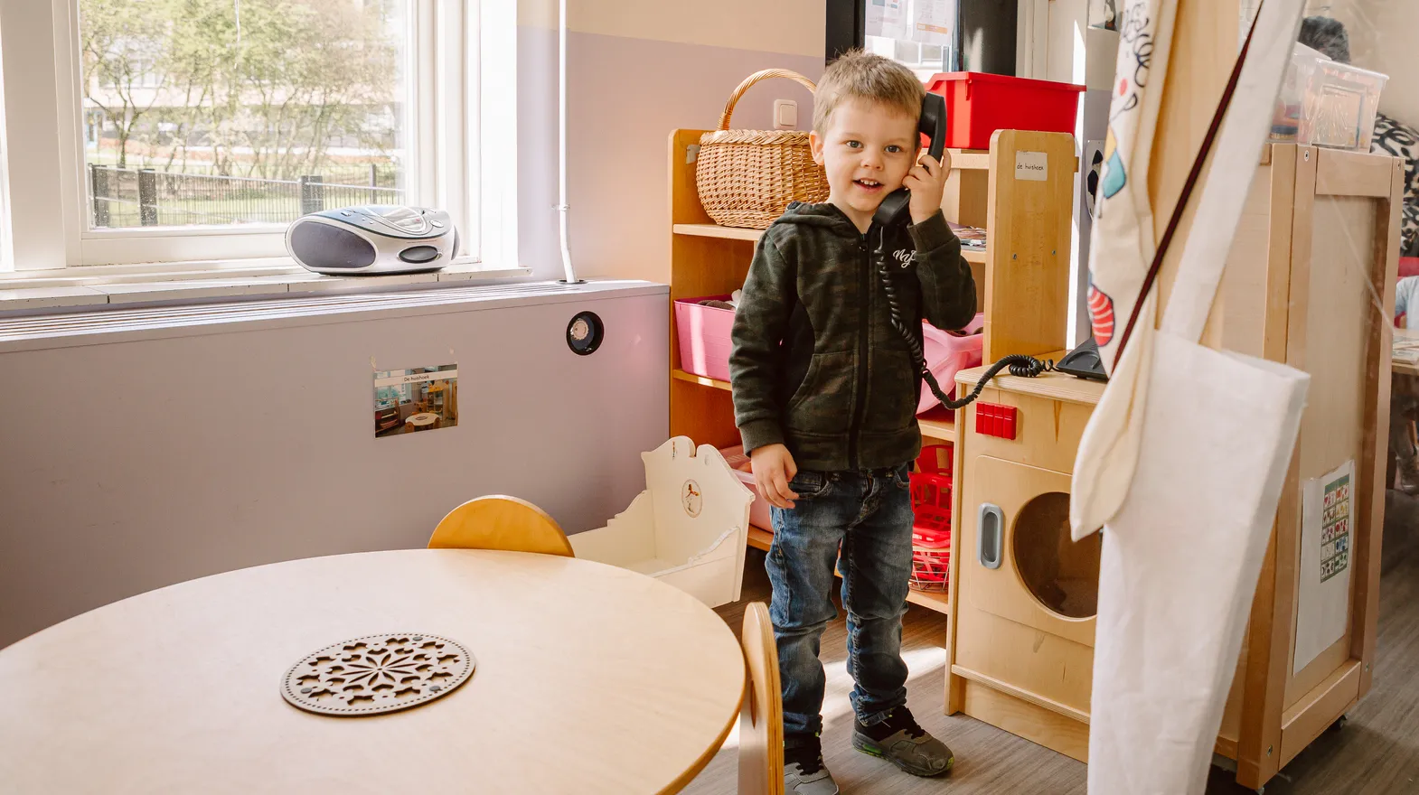 Kind belt met een speelgoedtelefoon bij peuteropvang De Kleine Wijzer, kinderopvang Kind&co ludens
