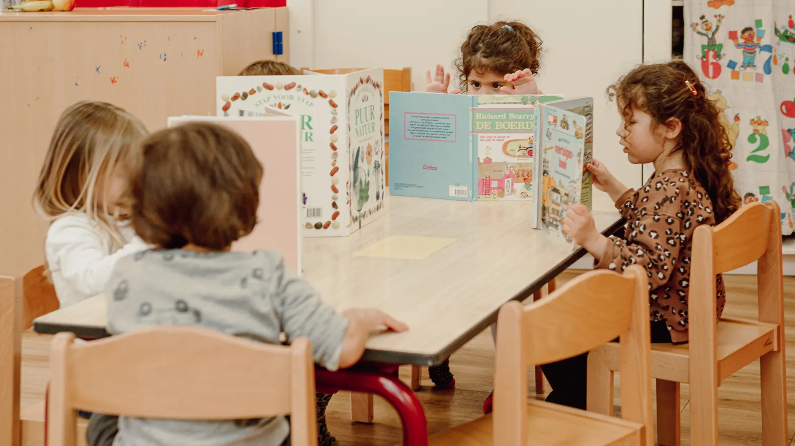Kinderen van de peutergroep lezen samen aan tafel bij kinderopvang Kind&co ludens