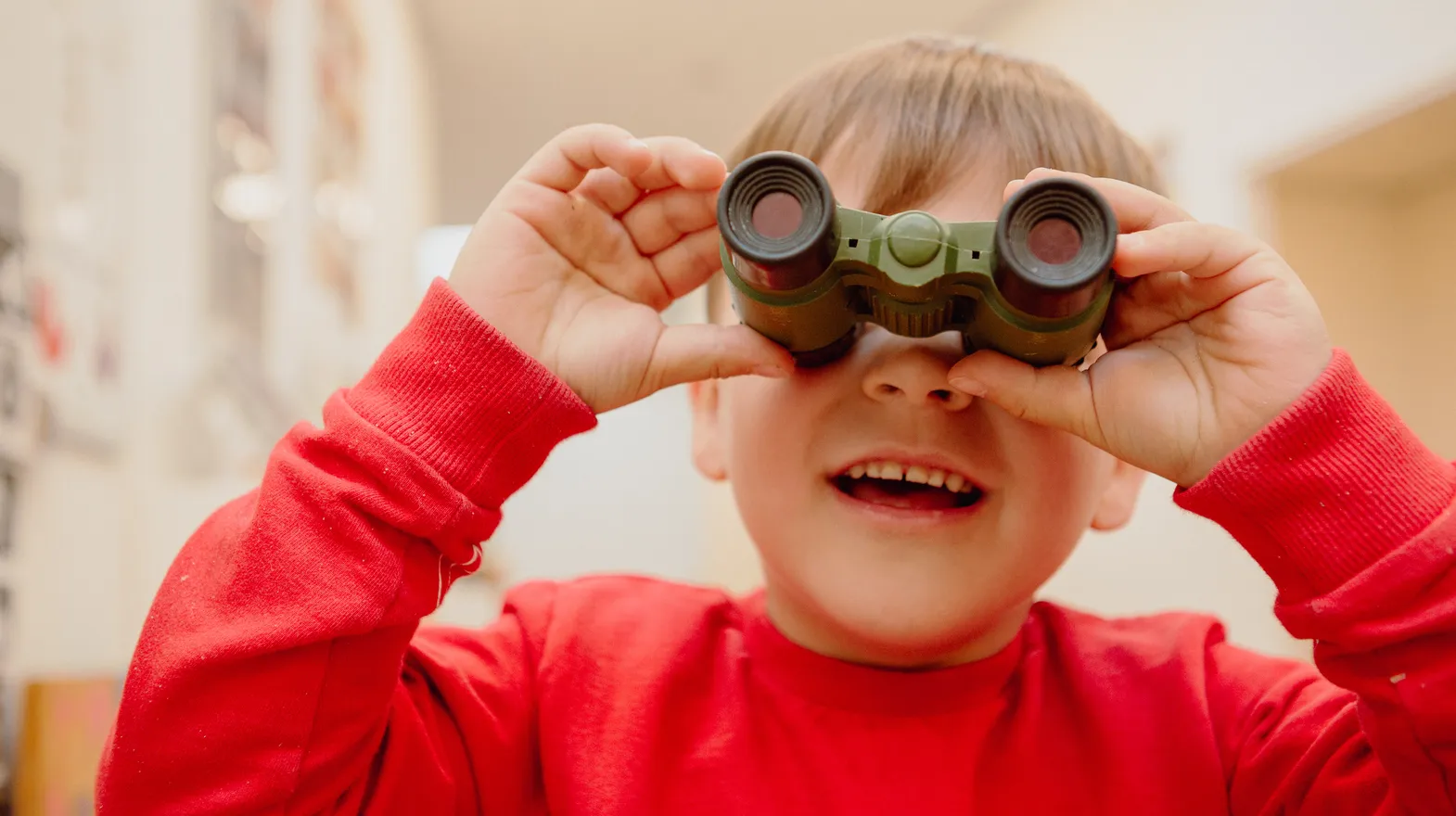 Kind kijkt door een verrekijker bij een Peutergroep van kinderopvang Kind&co ludens