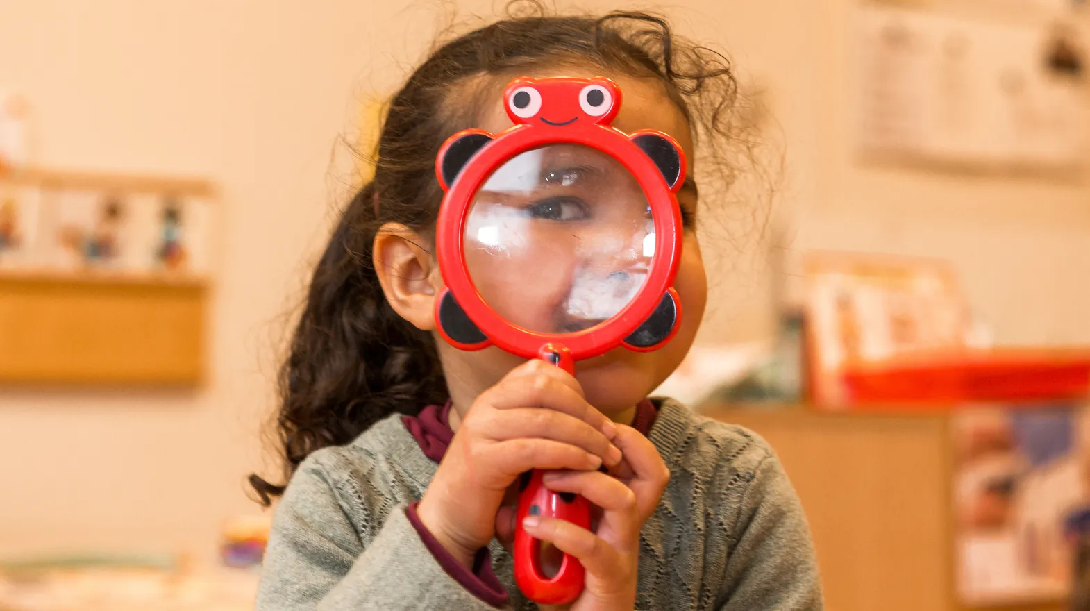 Kind op de peutergroep speelt met vergrootglas bij kinderopvang Kind&co ludens