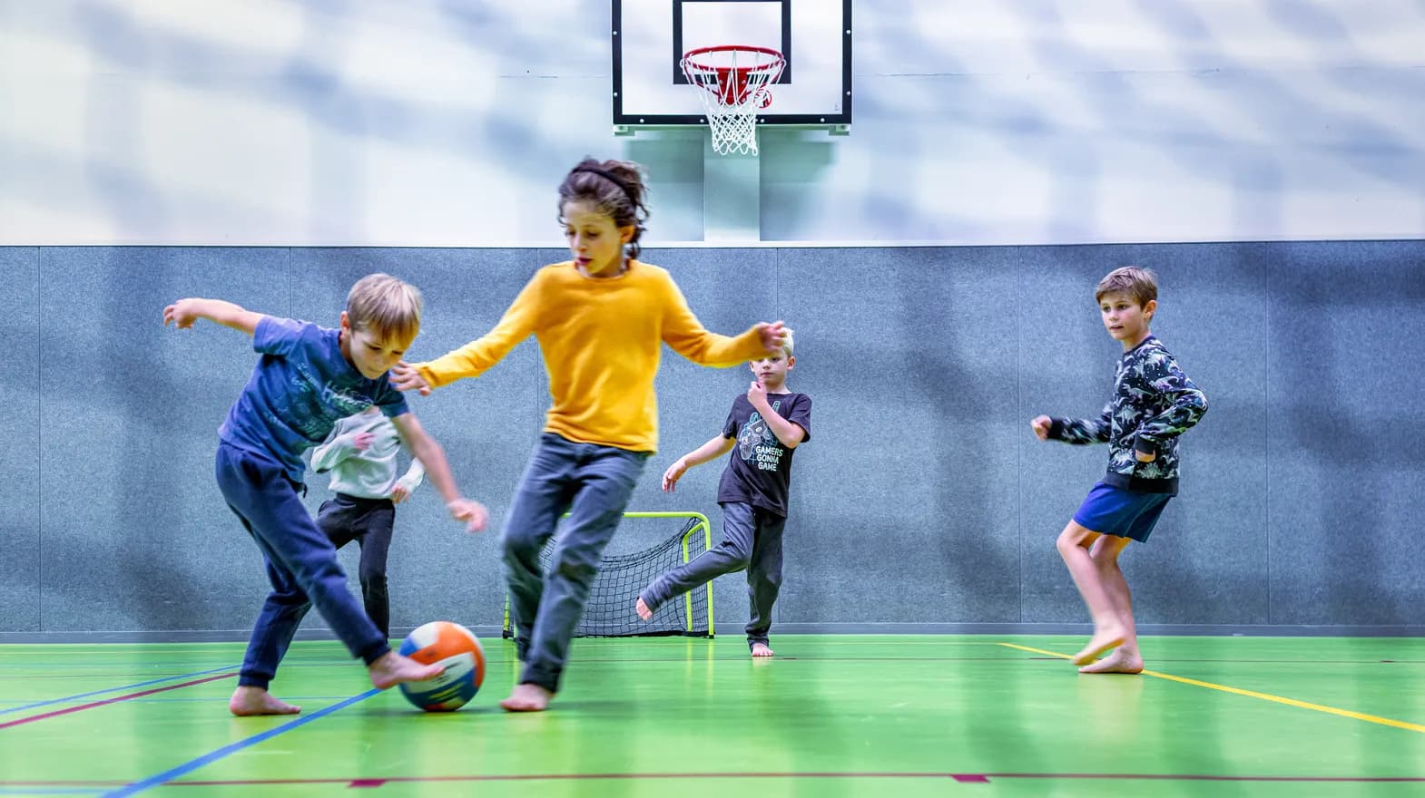 Kinderen van de BSO spelen samen voetbal in de gymzaal bij kinderopvang Kind&co ludens