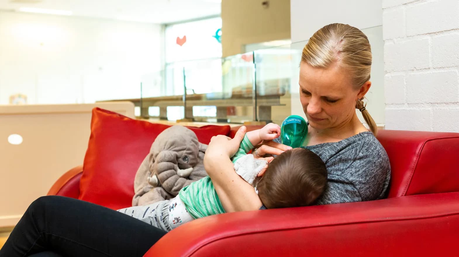 Pedagogisch medewerker geeft een baby de fles bij kinderdagverblijf Het Palet, kinderopvang Kind&co ludens