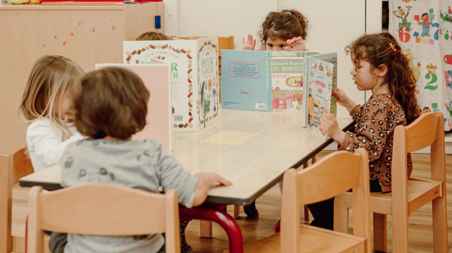Kinderen van de peutergroep lezen samen aan tafel bij kinderopvang Kind&co ludens