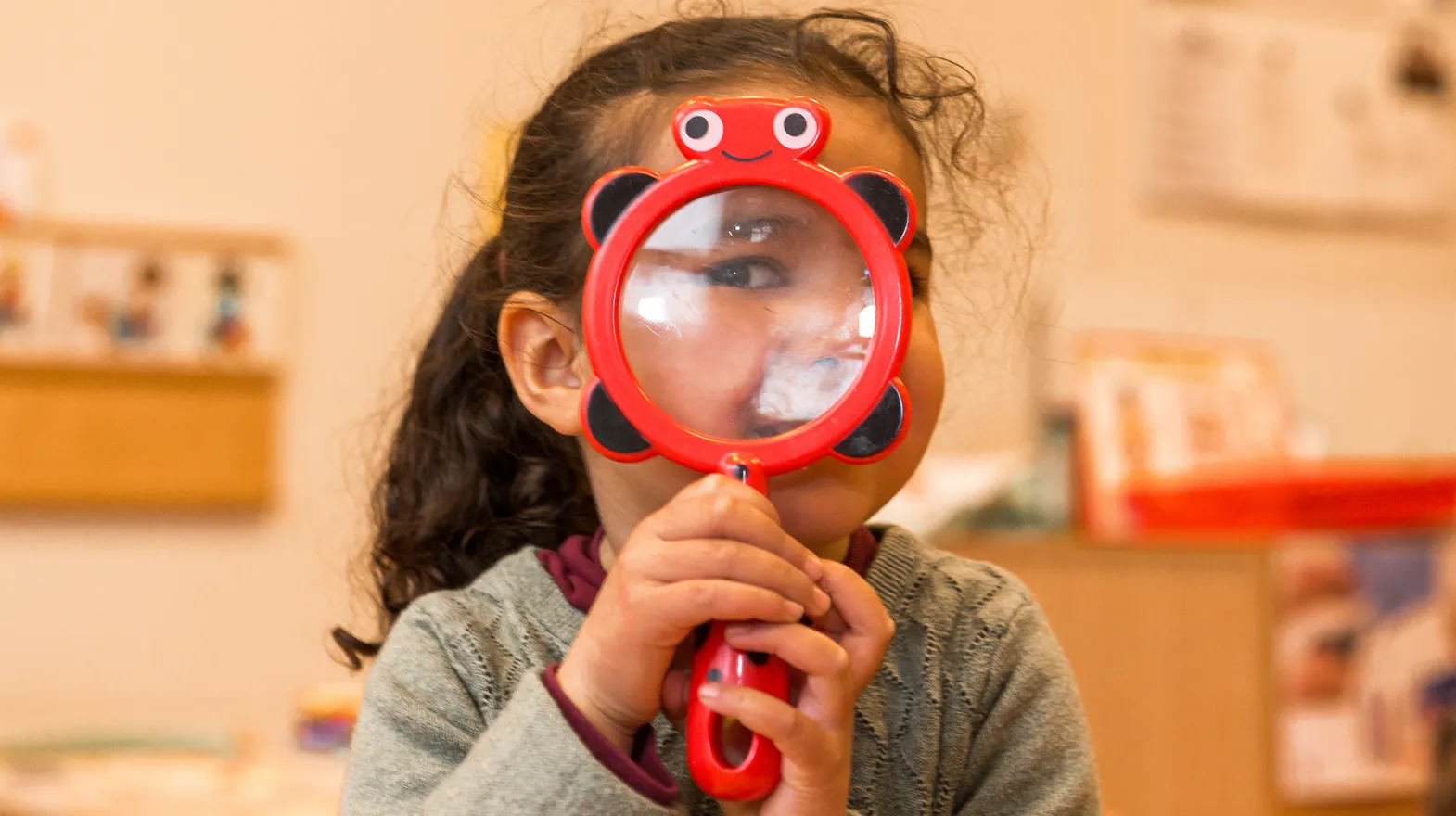 Kind op de peutergroep speelt met vergrootglas bij kinderopvang Kind&co ludens