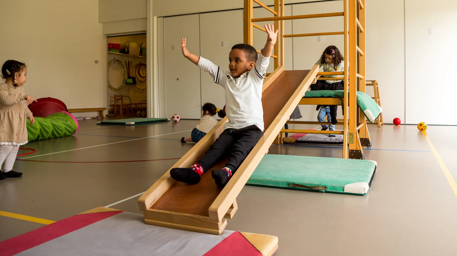 Kinderen klimmen en glijden in gymzaal bij kinderopvang Kind&co ludens