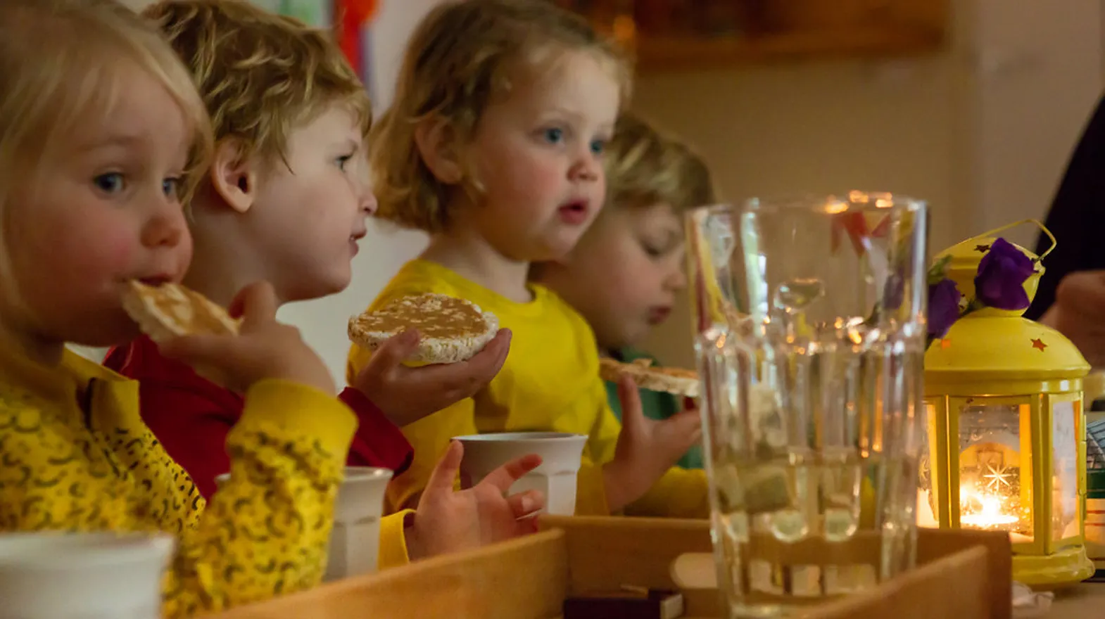 Kinderen zitten aan tafel en eten een rijstwafel bij kinderdagverblijf Rozenrood, kinderopvang Kind&co ludens