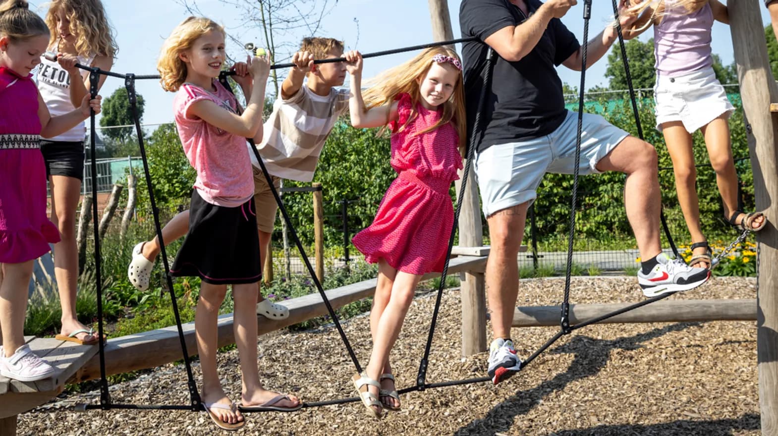 Kinderen spelen buiten met pedagogisch medewerker bij kinderopvang Kind&co ludens