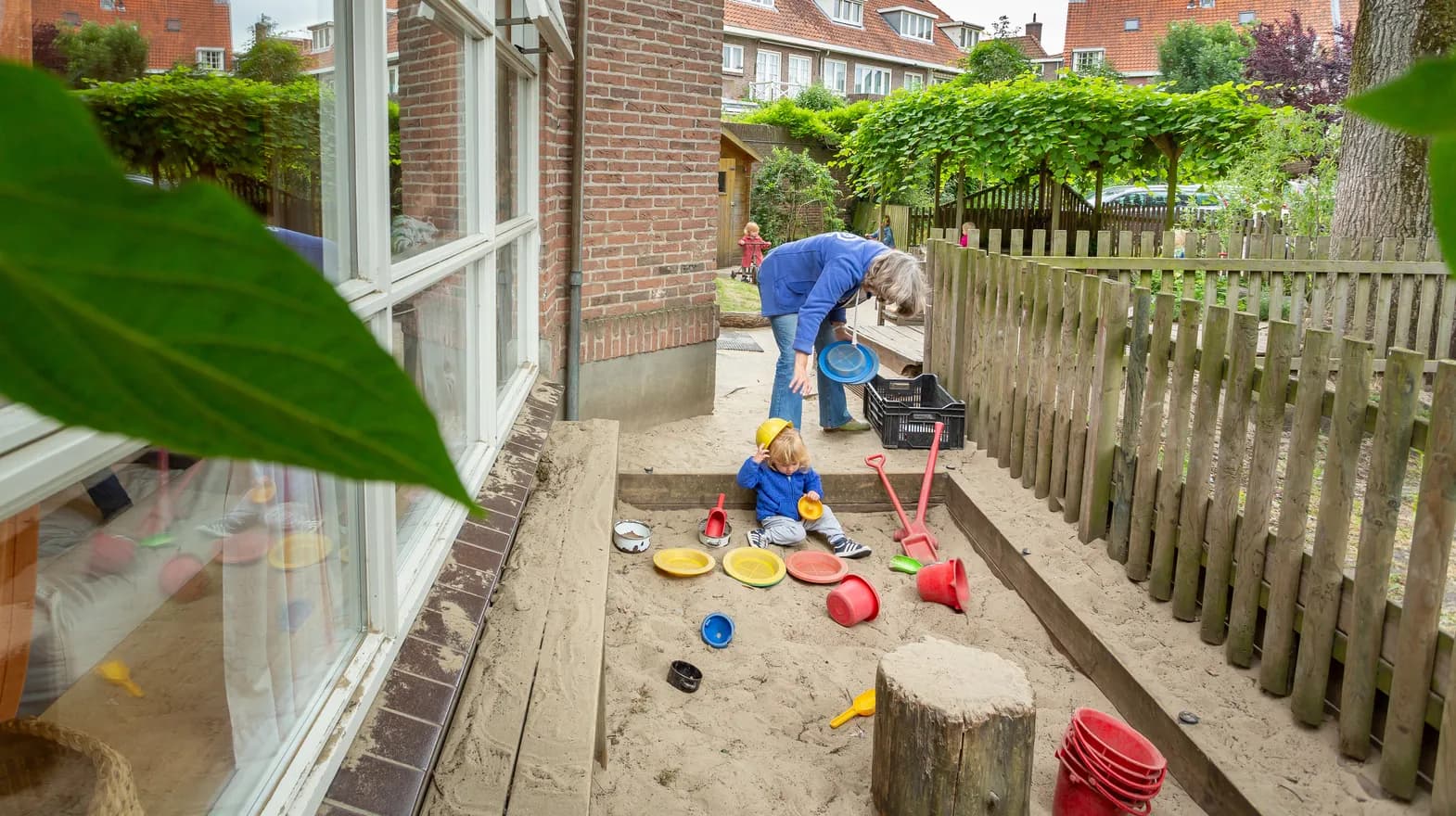 Kind speelt buiten in zandbak bij kinderdagverblijf 't Elfenbankje, kinderopvang Kind&co ludens