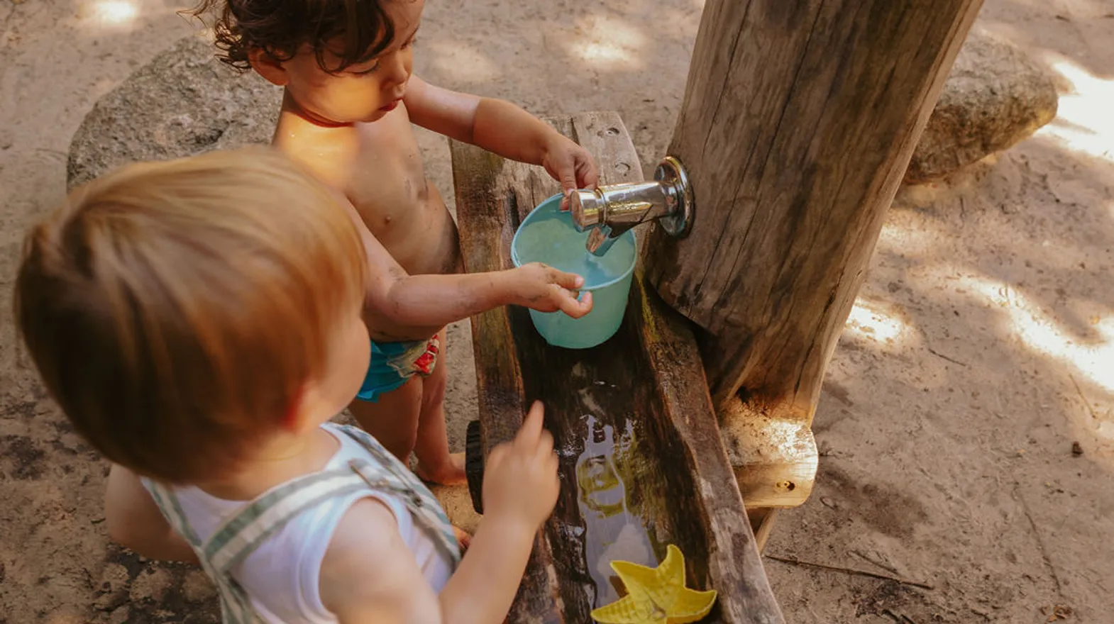 Kinderen spelen buiten met modder en water bij kinderopvang Kind&co ludens