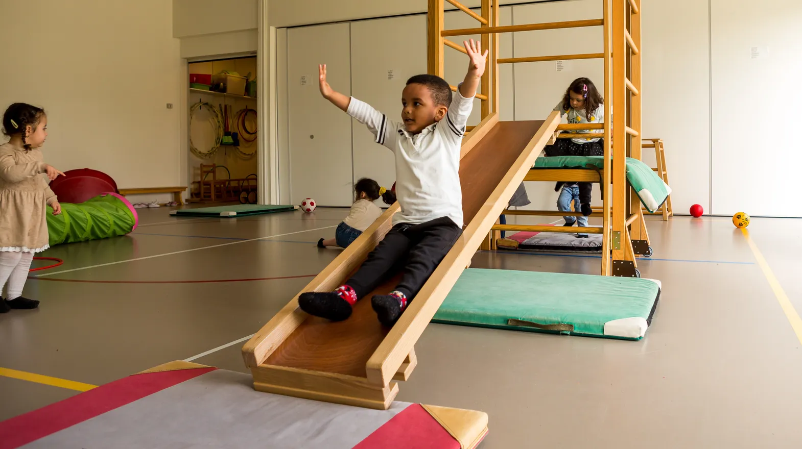 Kinderen klimmen en glijden in gymzaal bij kinderopvang Kind&co ludens