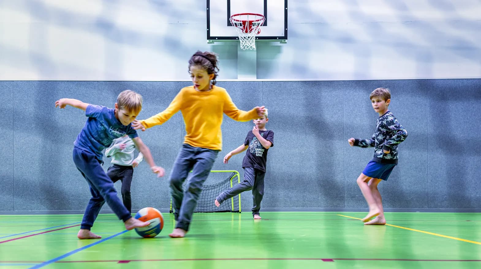 Kinderen van de BSO spelen samen voetbal in de gymzaal bij kinderopvang Kind&co ludens