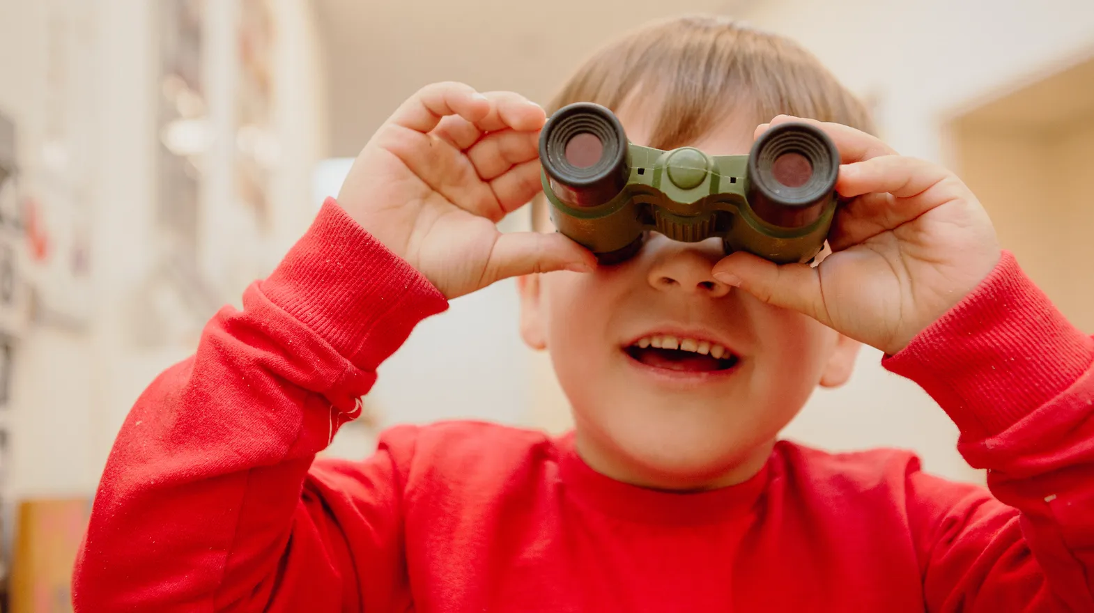 Kind kijkt door een verrekijker bij een Peutergroep van kinderopvang Kind&co ludens