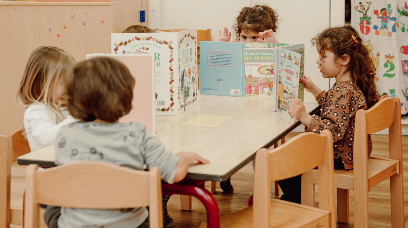 Kinderen van de peutergroep lezen samen aan tafel bij kinderopvang Kind&co ludens