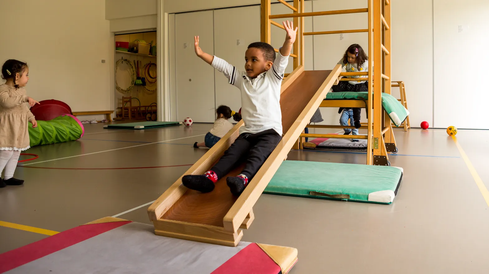 Kinderen klimmen en glijden in gymzaal bij kinderopvang Kind&co ludens