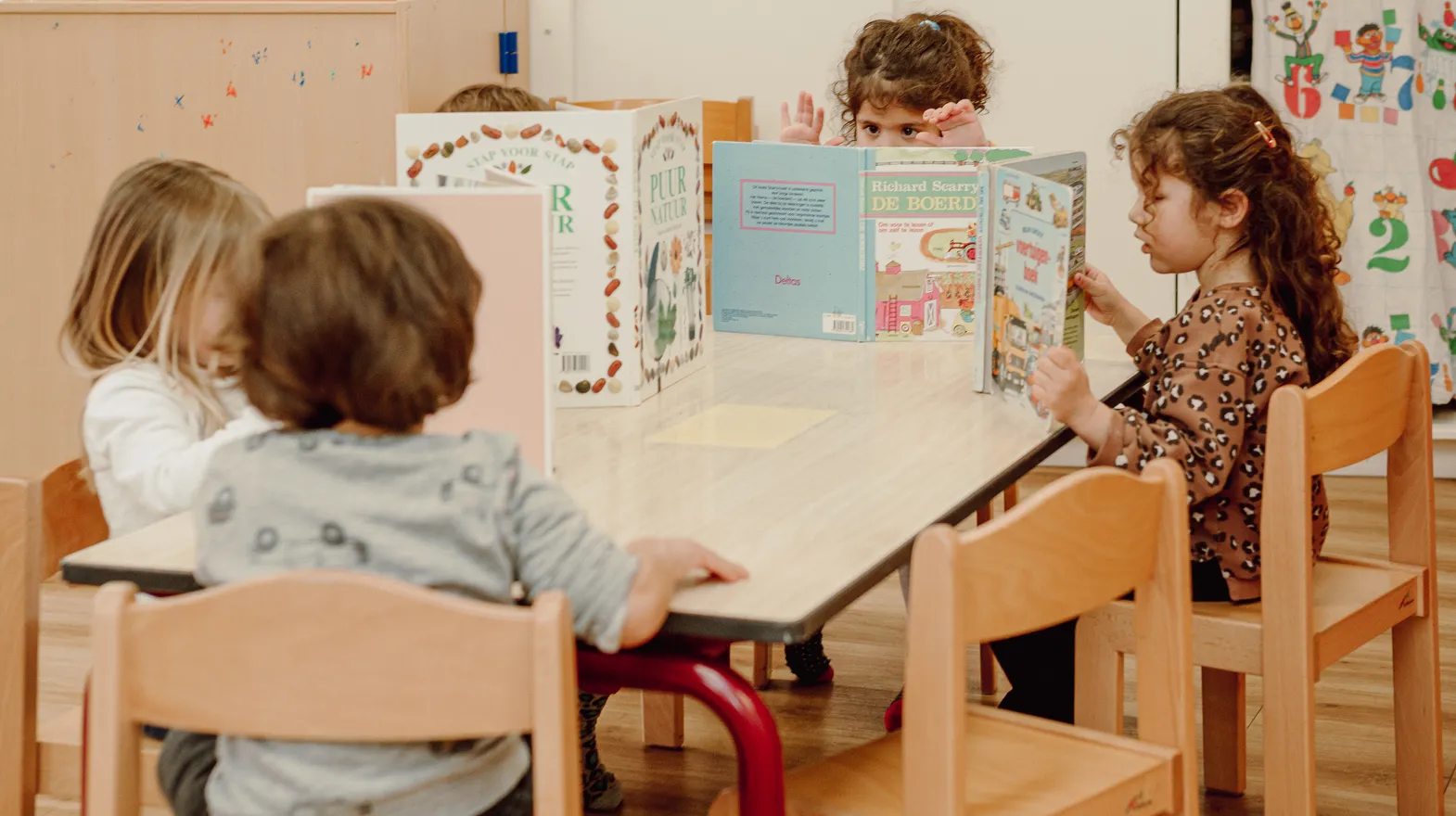 Kinderen van de peutergroep lezen samen aan tafel bij kinderopvang Kind&co ludens
