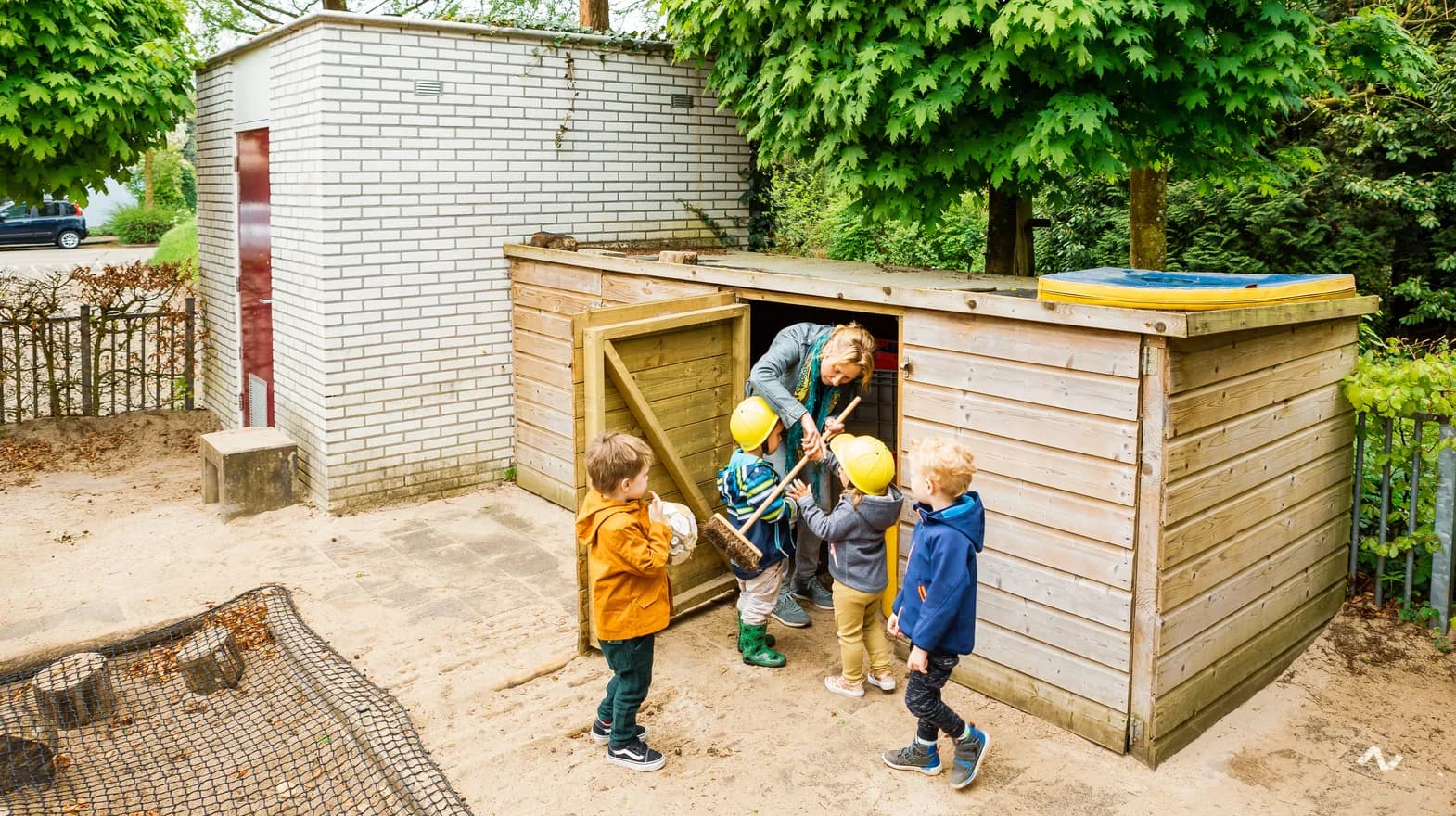 Kinderen pakken speelgoed uit de schuur bij kinderdagverblijf Villa Kakelbont, kinderopvang Kind&co ludens