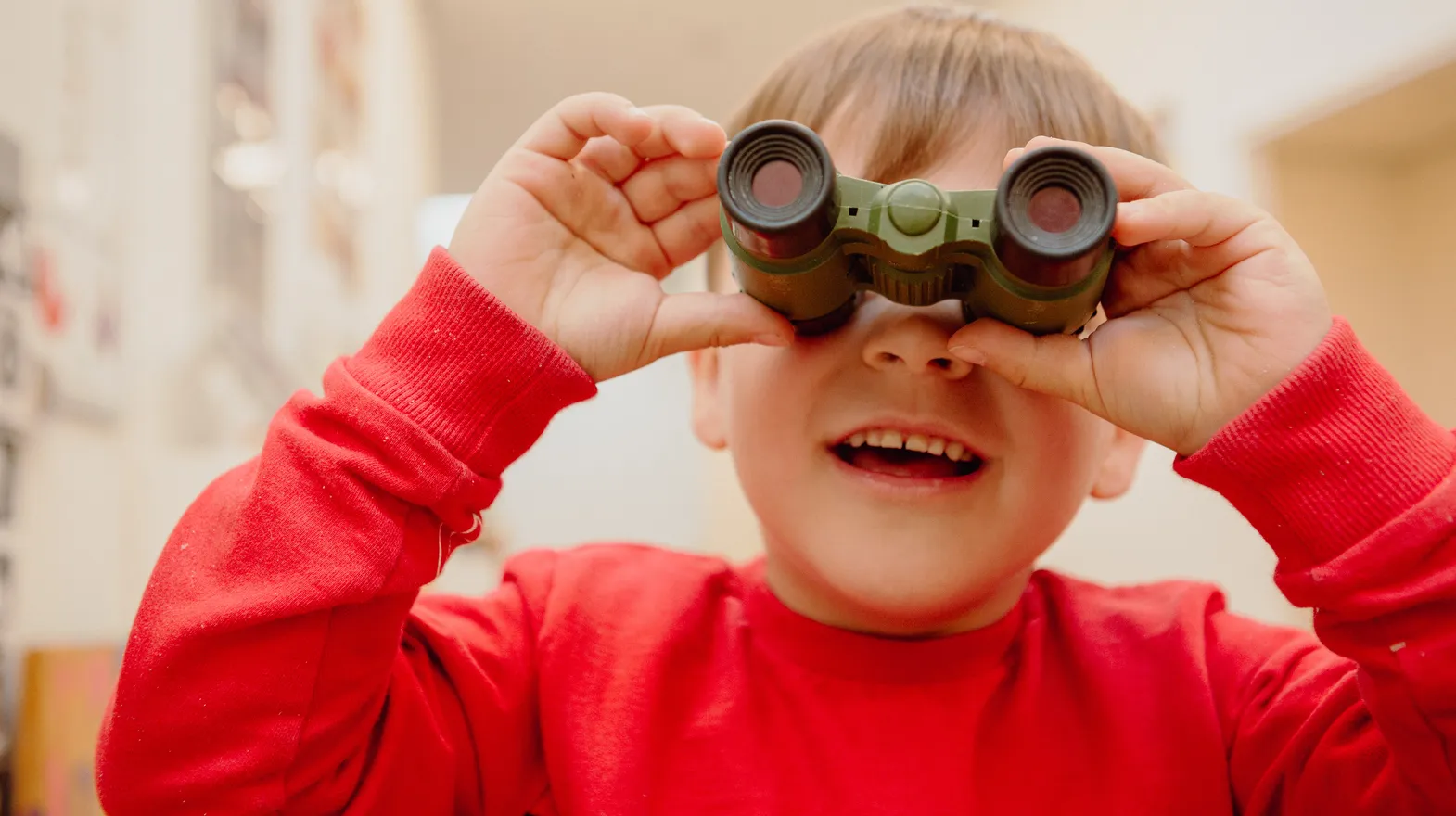 Kind kijkt door een verrekijker bij een Peutergroep van kinderopvang Kind&co ludens