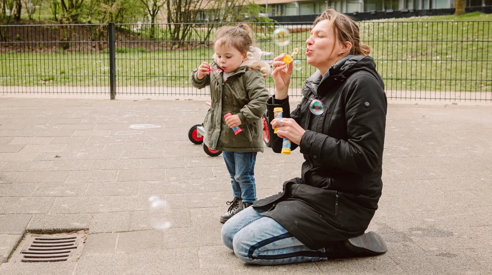 Pedagogisch medewerker en kind blazen bellen bij peuteropvang De Kleine Wijzer, kinderopvang Kind&co ludens